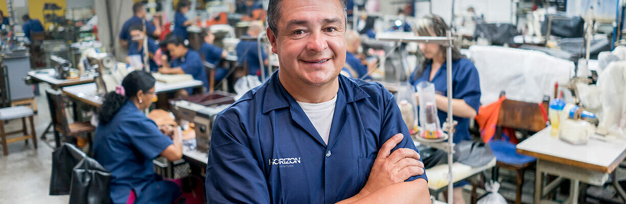 Horizon people in the factory Happy adult Latin American man working at a shoe-making factory and looking at the camera smiling
